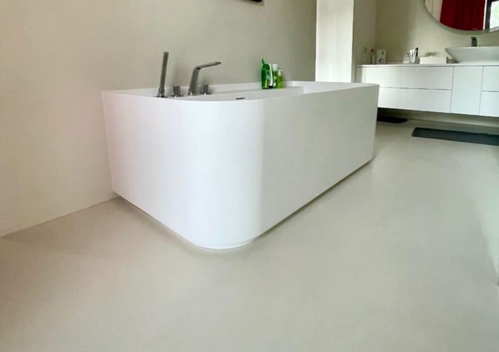 Inspiracje łazienka - Łazienka z beżowym mikrocementem i nowoczesną wanną, tworząca eleganckie i nowoczesne wnętrze.