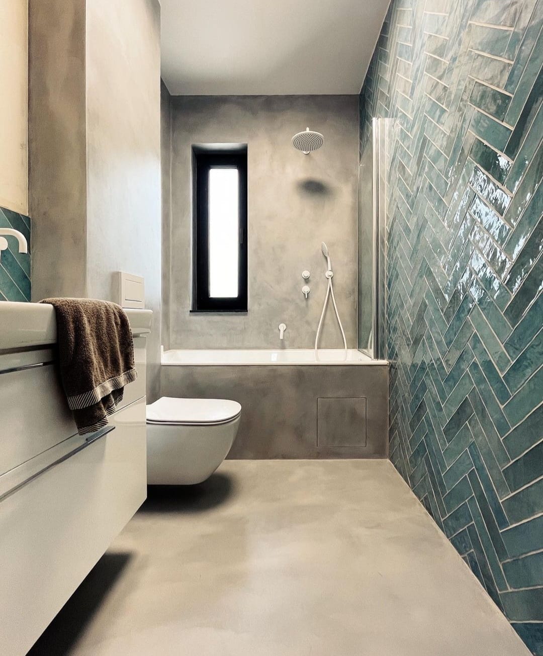 Inspiracje łazienka - Nowoczesna łazienka z mikrocementowymi podłogami i unikalnymi niebieskimi kafelkami na jednej ze ścian, prezentująca nowoczesny design.