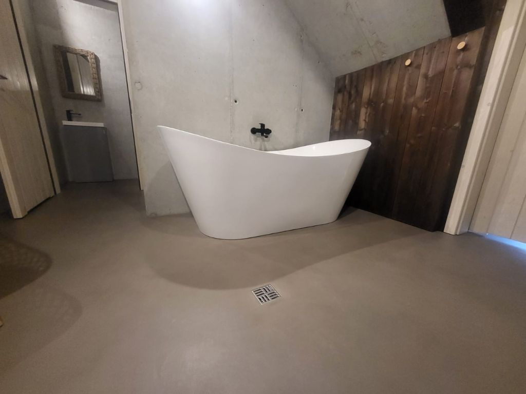 Inspiracje łazienka - Nowoczesna łazienka z nowoczesną wanną i surowymi ścianami z betonu architektonicznego, tworząca wyjątkowy design.